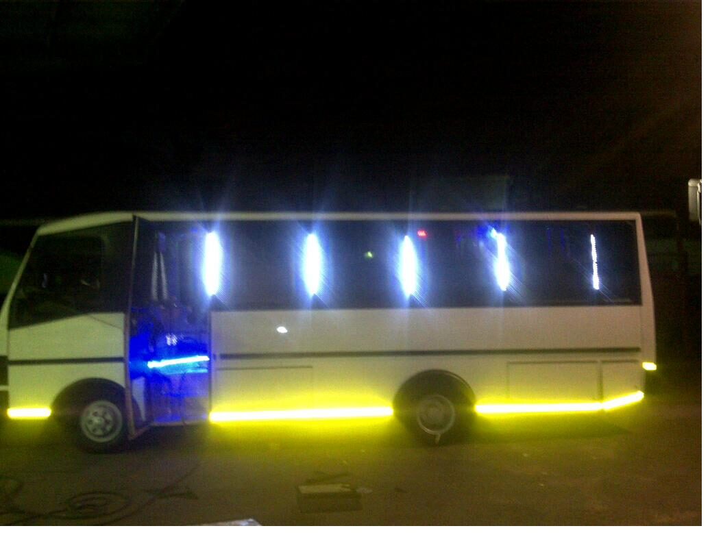 Party bus lit up with neon underglow lighting at night