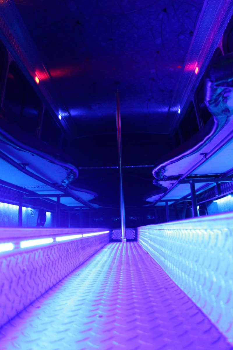 Violet LED lighting along a party bus dance floor aisle