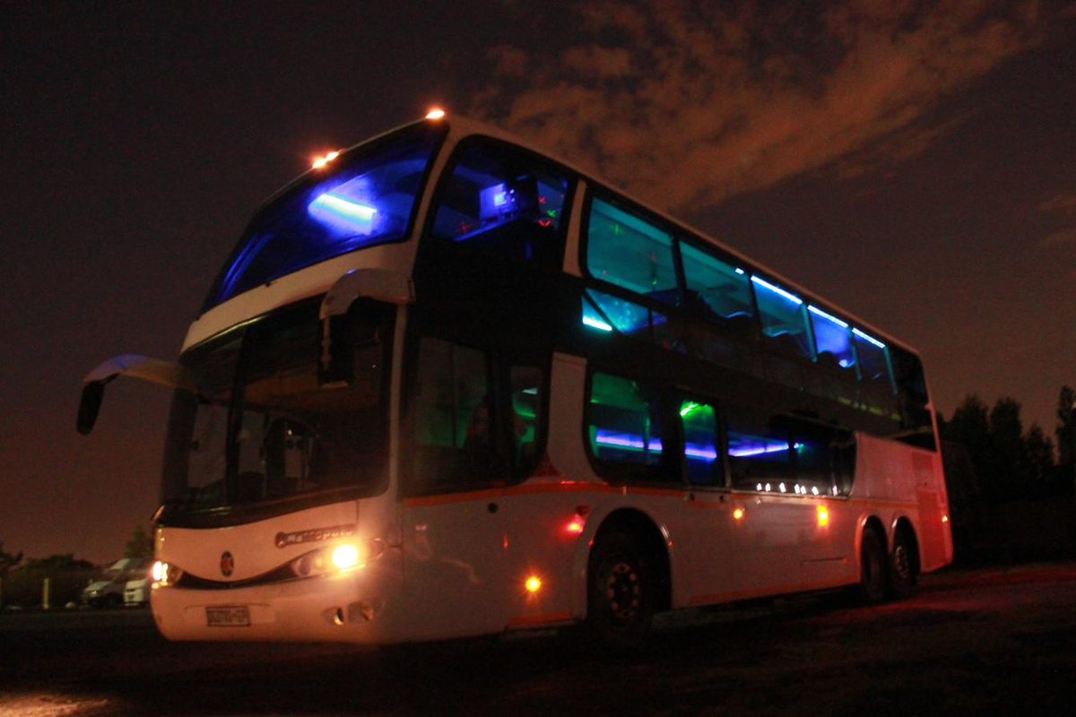 Double decker party bus with interior lighting visible at night
