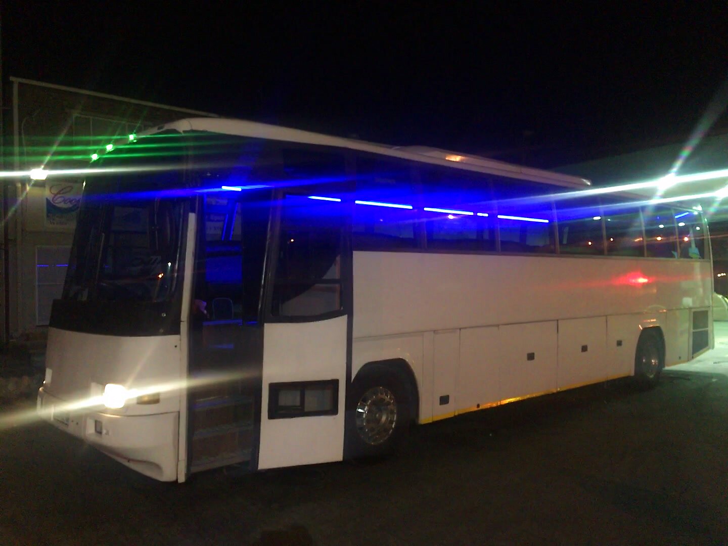 Party bus with blue LED strip and green laser beams at night